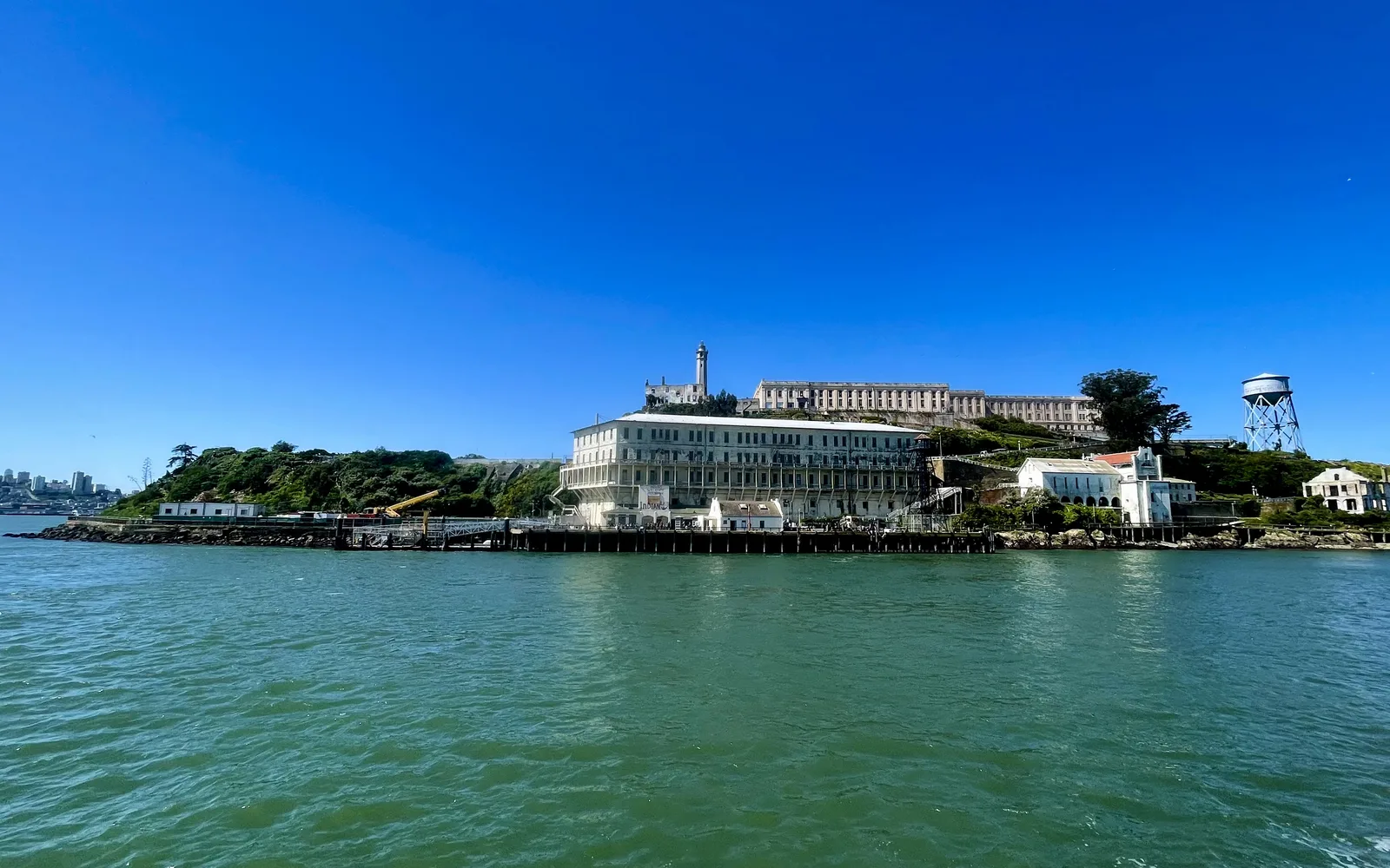 Alcatraz Island in San Francisco Bay, showing the historic prison buildings and structures with the water and distant shoreline